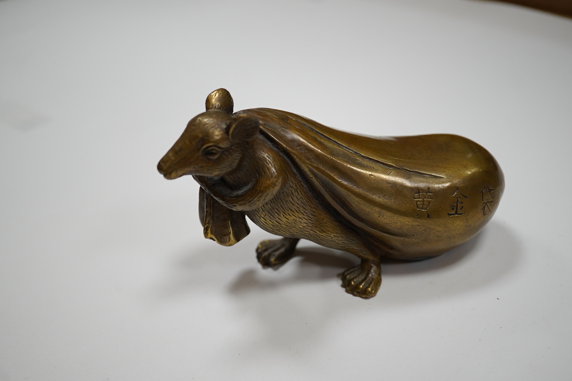 A Chinese bronze rat carrying a sack, signed in casting, 14cm long. Condition - fair